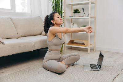 Side view of young woman sitting on sofa at home