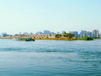 Scenic view of sea and buildings against clear sky