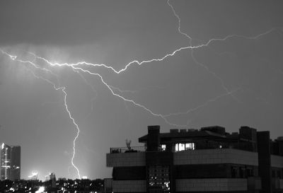 Low angle view of lightning over city at night