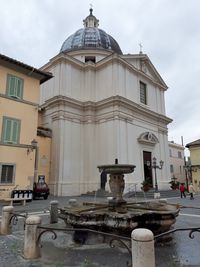 Fountain by building against sky in city