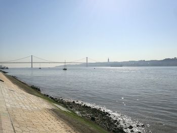 Bridge over calm sea against clear sky