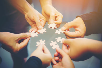 Close-up of people holding jigsaw pieces