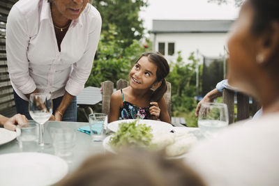 Midsection of senior woman taking to family at outdoor dining table
