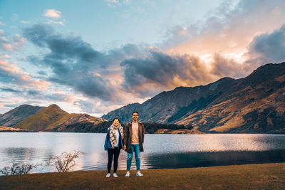 Rear view of people standing on lake against mountains