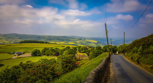 Scenic view of road amidst trees against sky