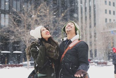 Couple enjoying snowfall during winter in city