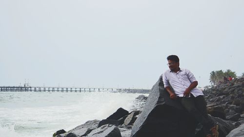 Young man on beach against clear sky