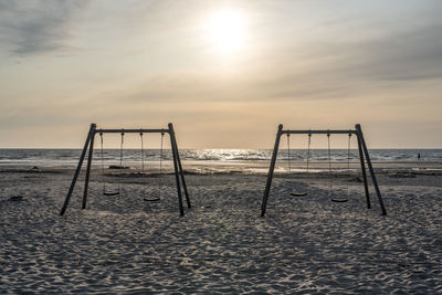 Lifeguard hut on beach against sky during sunset