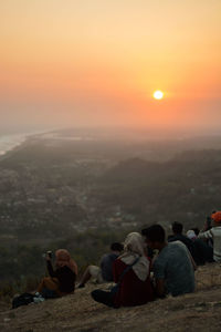 People relaxing on rocks at sunset