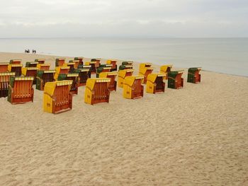 Deck chairs on beach against sky