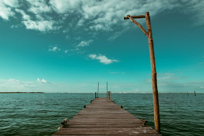 Pier on sea against cloudy sky