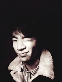 Close-up portrait of smiling boy against black background
