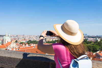 Rear view of woman with hat against sky in city