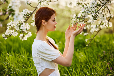 Side view of young woman standing amidst plants