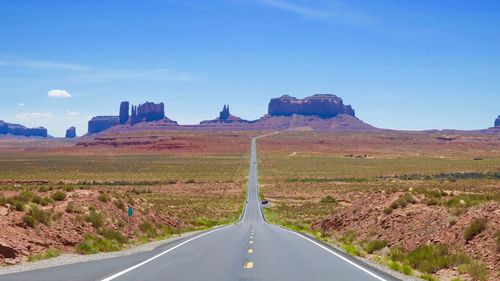 Empty road by landscape against sky