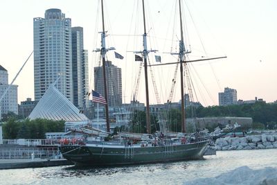 Sailboats moored on sea against buildings in city