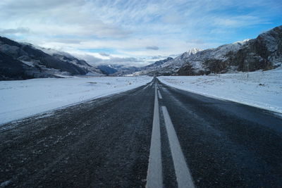 Road amidst snow covered mountains against sky