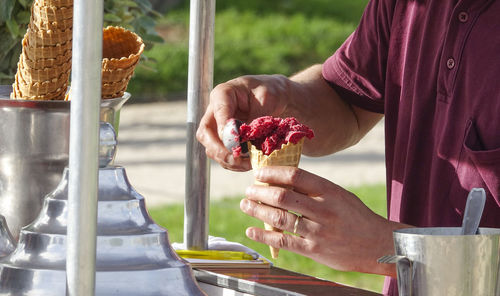 Midsection of man holding ice cream on table