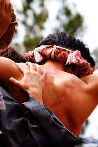 Rear view of people carrying man for crucifix outdoors