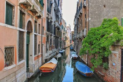 Boats moored in canal amidst buildings in city