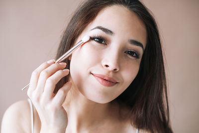 Close-up of young woman applying make-up