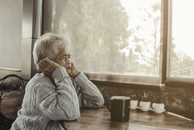 Old person sitting by coffee cup on table at home. concept loneliness, dementia, abuse, sadness.