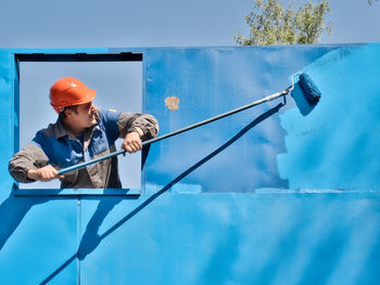 Low angle view of man standing against blue sky