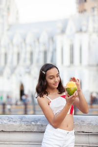Girl eating mango at the ortiz bridge with la ermita church on background in the city of cali