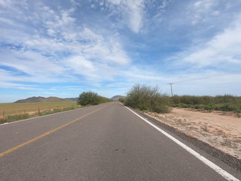 Road passing through land against sky