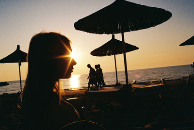 Silhouette people on beach against sky during sunset