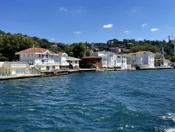 Buildings by sea against sky