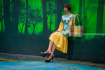 Female model sitting against patterned wall