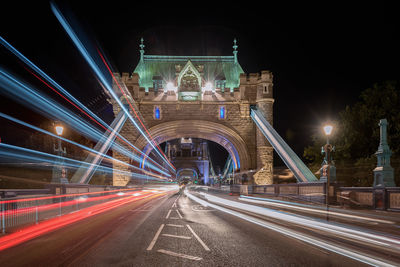 Light trails on tower bridge against sky at night