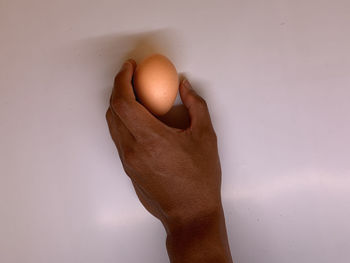 Close-up of hand holding ice cream over white background