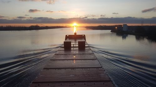 Pier over lake against sky during sunset