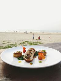 Close-up of food on table at beach against sky