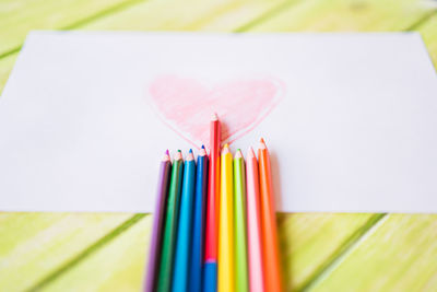 High angle view of paper with colored pencils on table