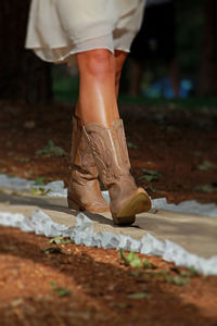 Low section of woman walking with leather boots on footpath