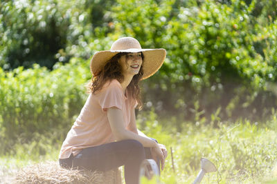 Woman wearing hat sitting on field