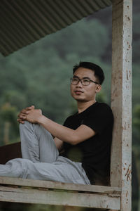 Full length of young man sitting outdoors