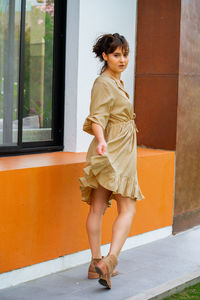 Full length of woman walking with style, wearing a beige dress and country style heels