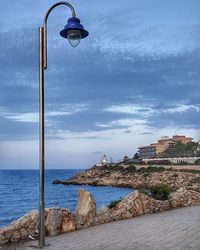 Street light by sea against sky