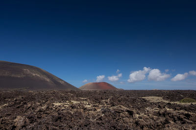 View of barren landscape against blue sky