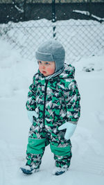 Cute boy in snow on field during winter