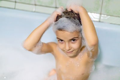 Portrait of cute girl taking bath in bathroom