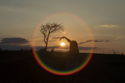 Rear view of girl seen through halo on land during sunset