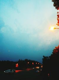 Cars on illuminated city against sky during sunset