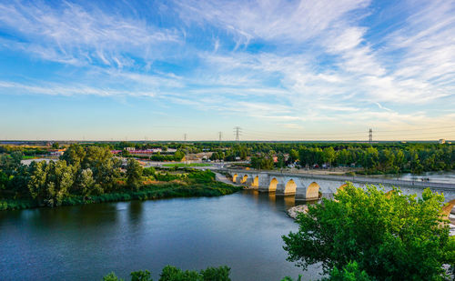 Arch bridge over river against sky in city