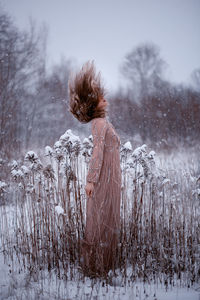 Rear view of woman standing on snow covered field
