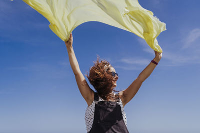 Low angle view of woman standing against blue sky